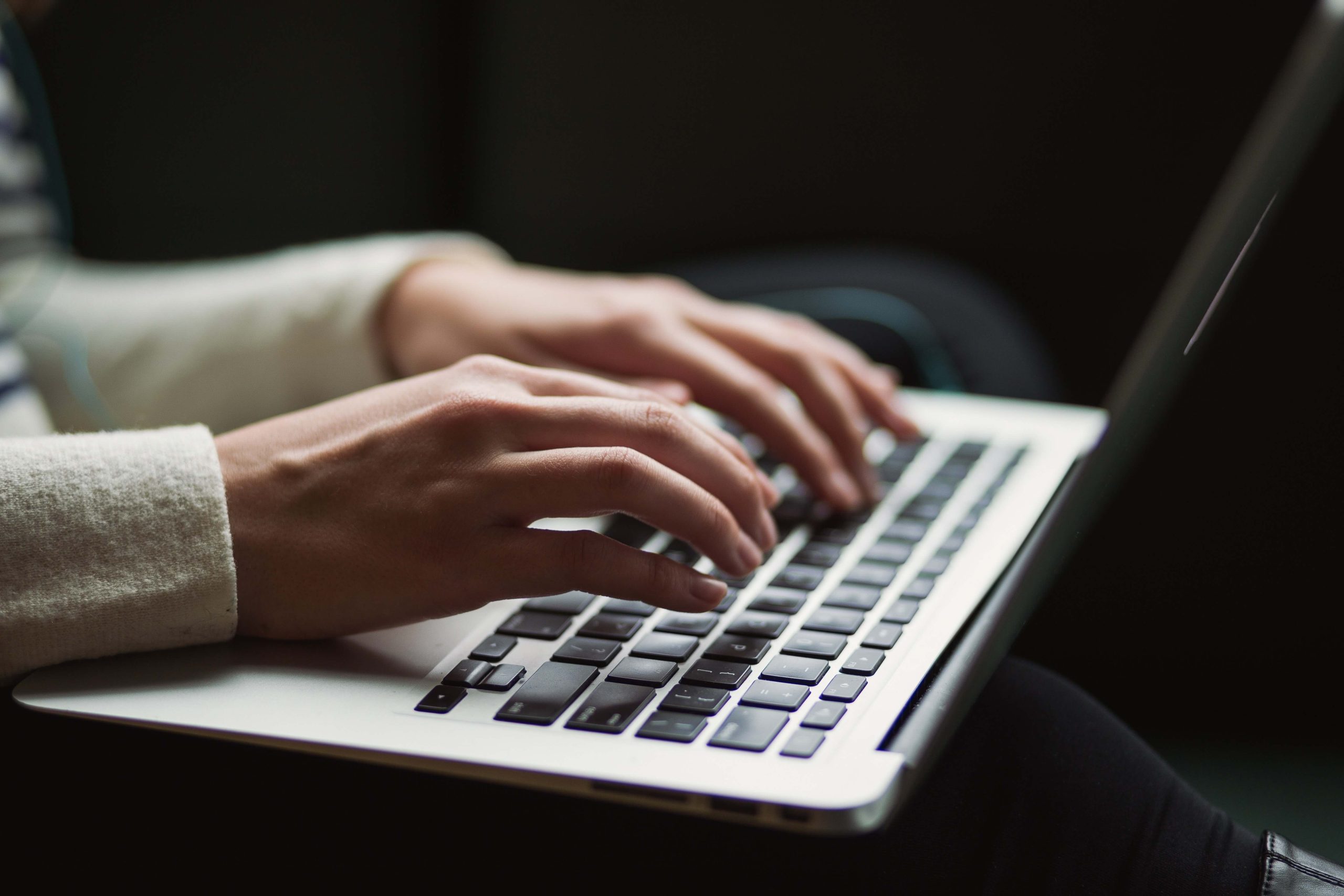 Close-up of a person's hands typing on a laptop.