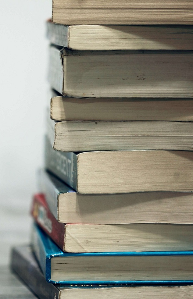 A stack of well-worn hardback books seen from the side.