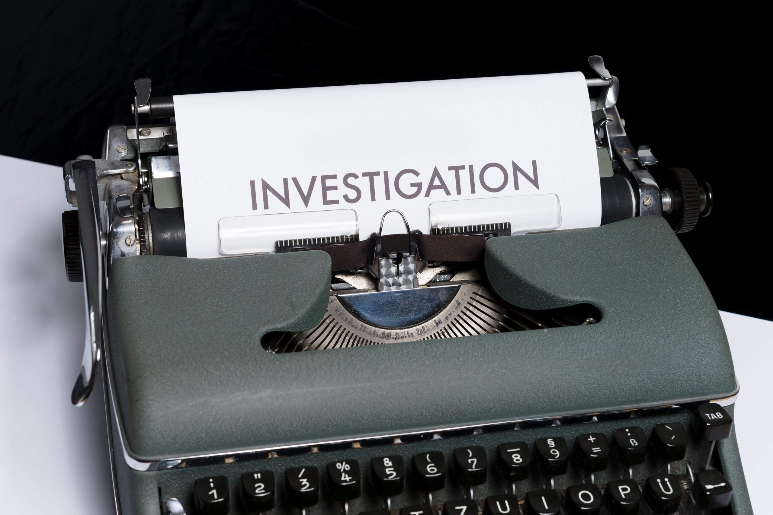 A typewriter with a sheet of paper in it bearing the single word "INVESTIGATION".