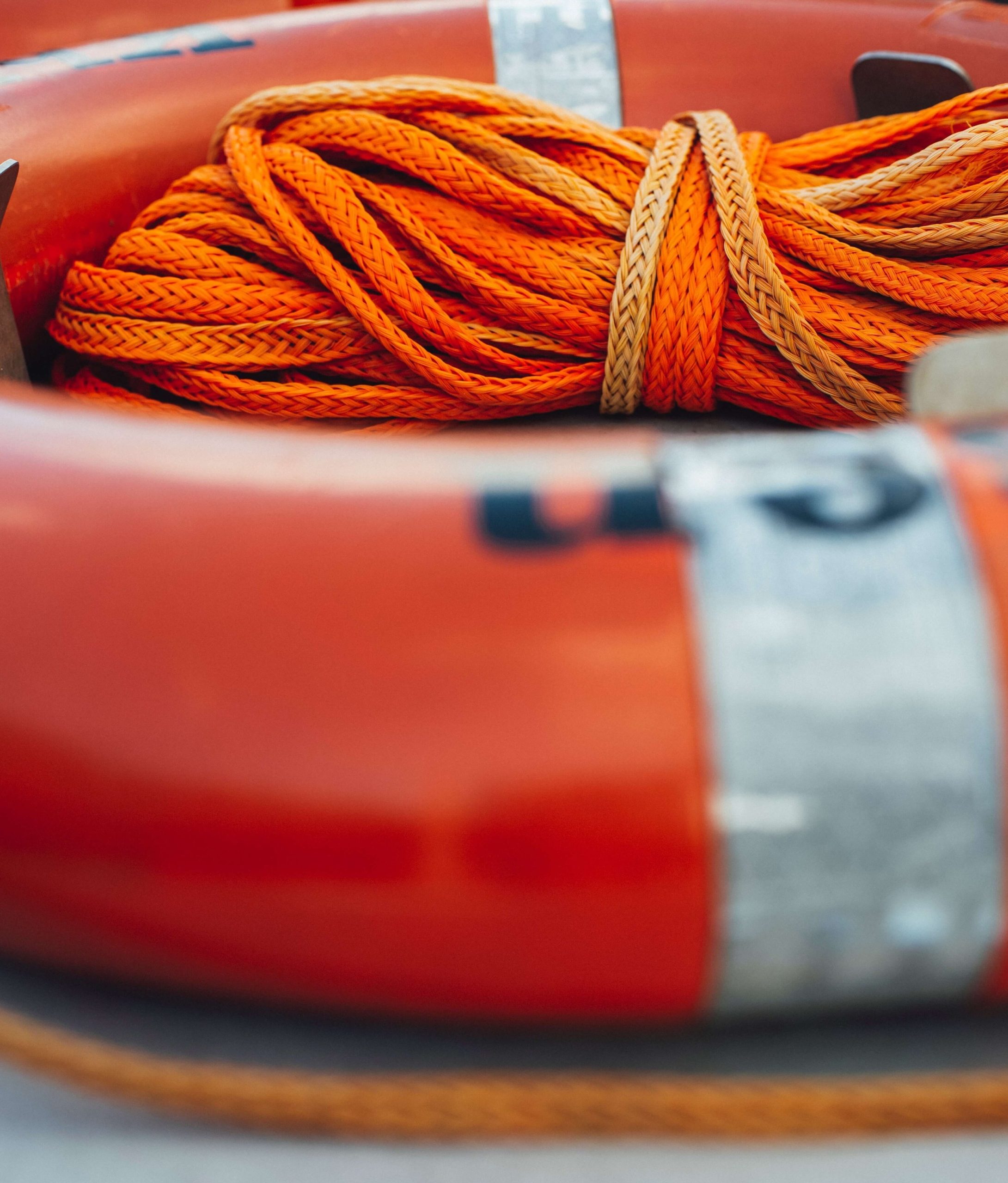 A close-up of an orange life ring with rope coiled on top of it.
