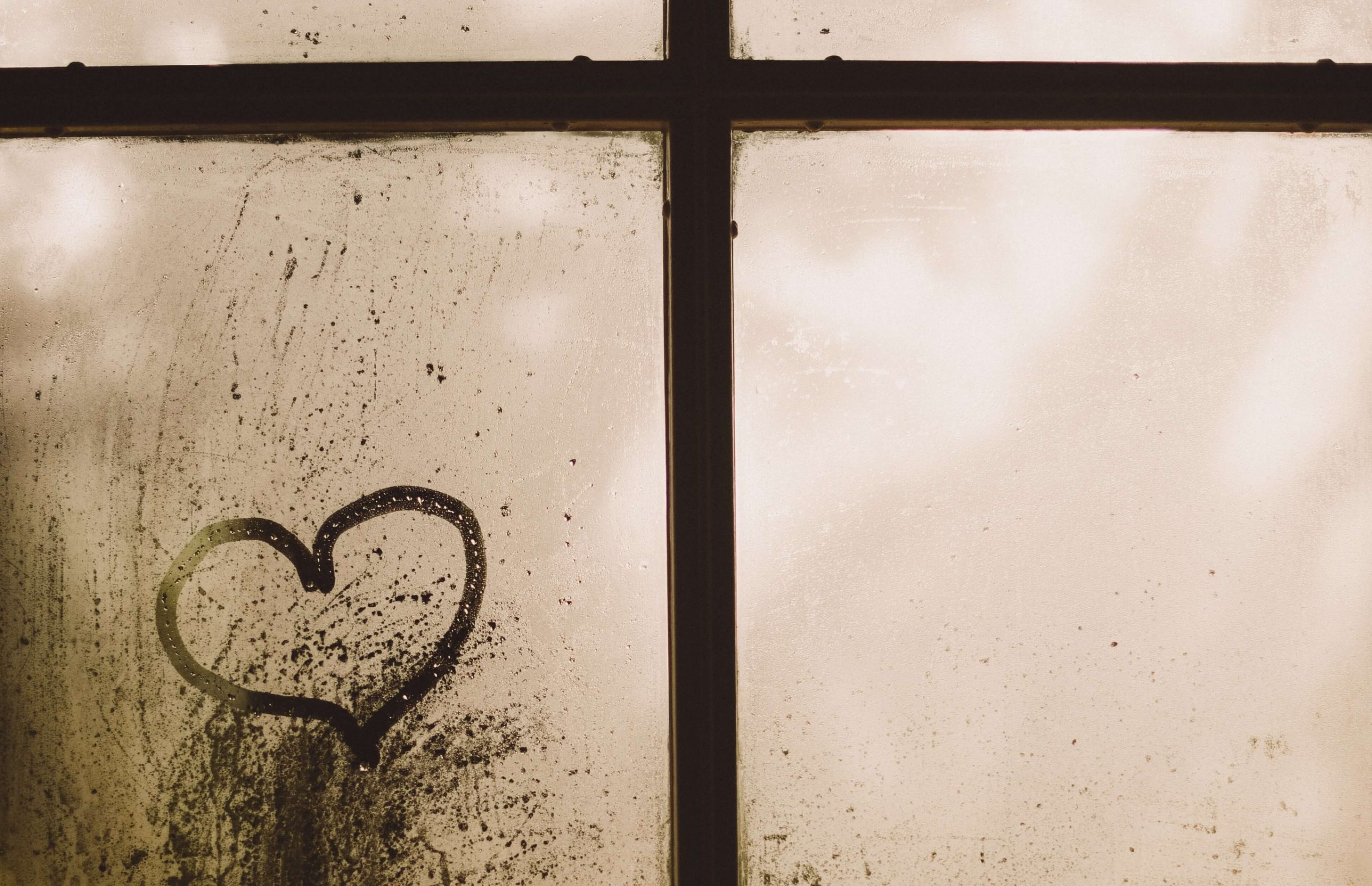 A heart drawn with a fingertip in the condensation on a window pane.