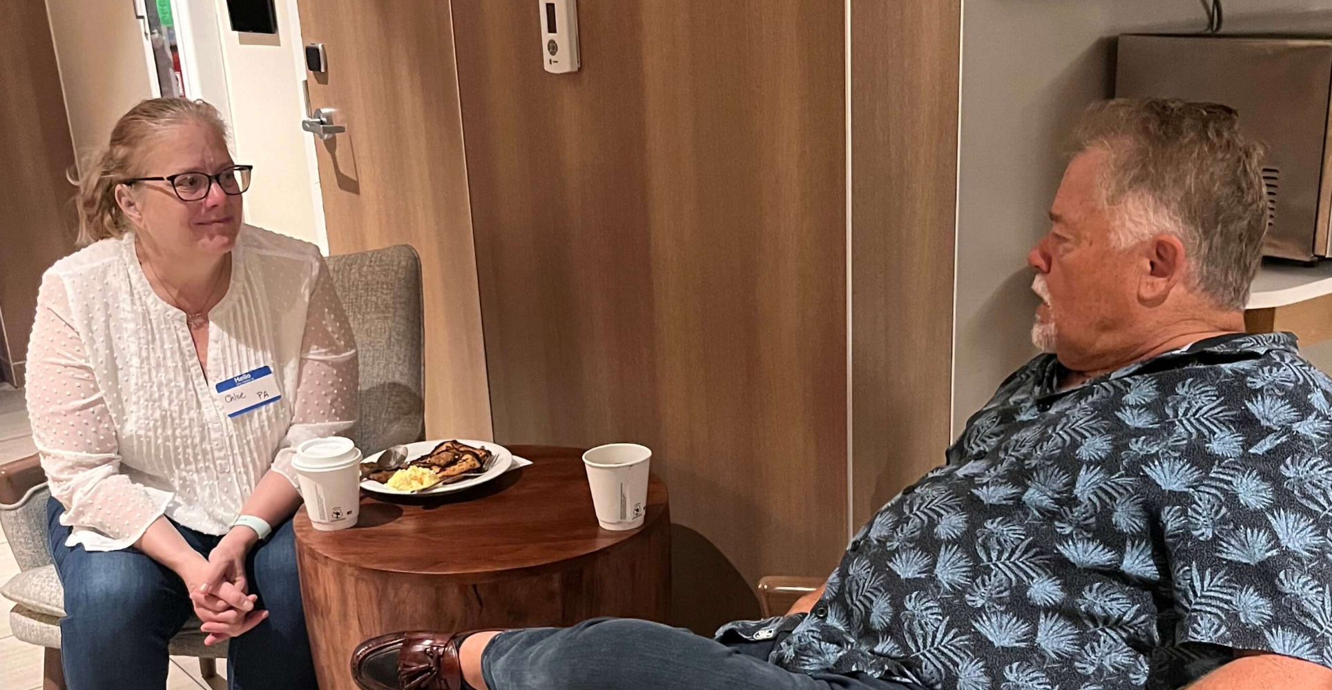 Forrest Lien, LCSW, shares a quiet conversation about developmental trauma with a parent during a morning gathering before the start of a previous NavRAD — a moment of connection before a full day of learning and healing begins.