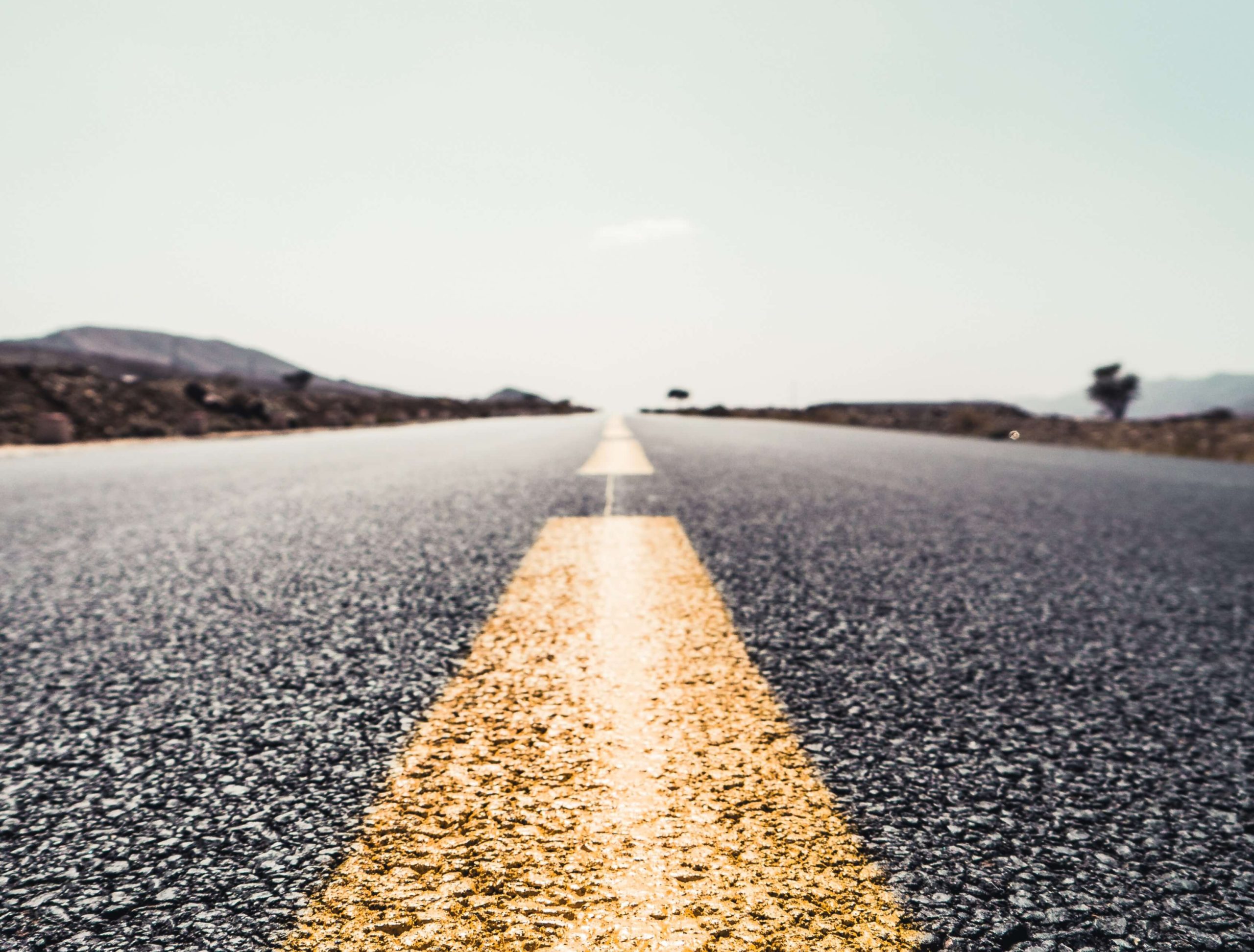 A long straight road stretching to the horizon, the centre line lit gold by low sun.