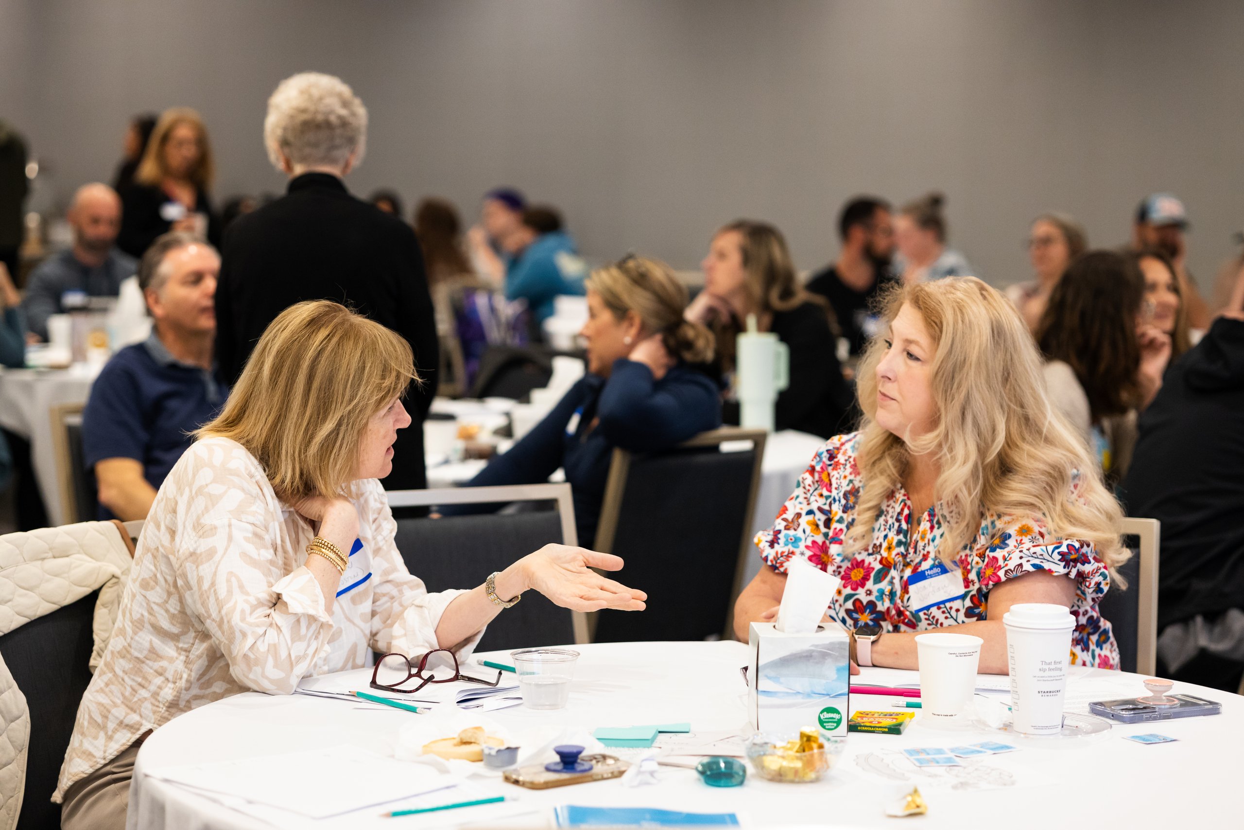 Two caregivers deep in conversation at a table during a NavRAD Experience session